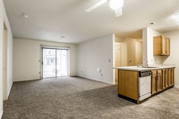 an empty living room with a kitchen and a door to a balcony at Pheasant Run in Lafayette, IN 47909